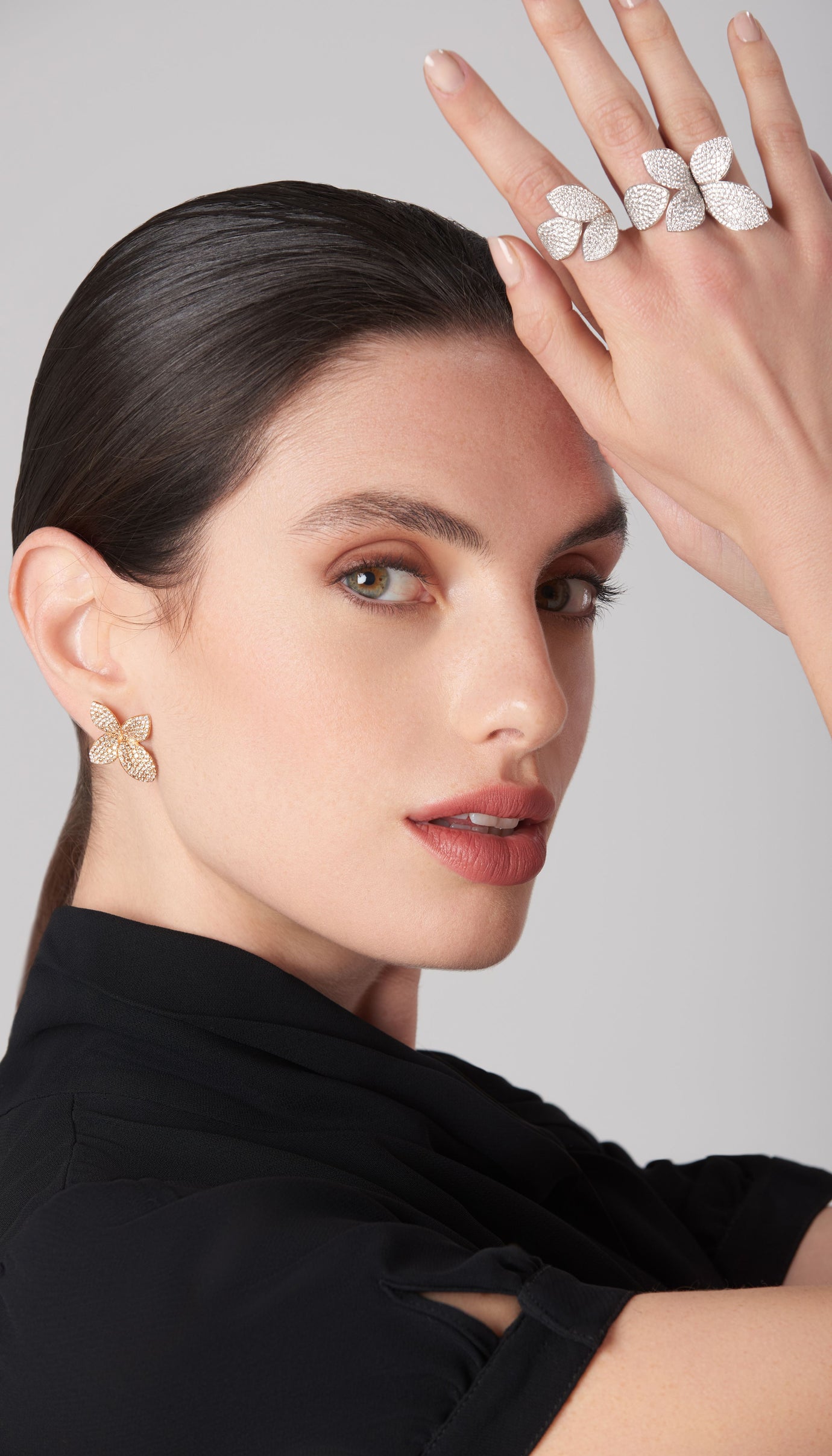 Earring and rings in 18k white and rose gold with diamonds worn by a model in a black silk blouse