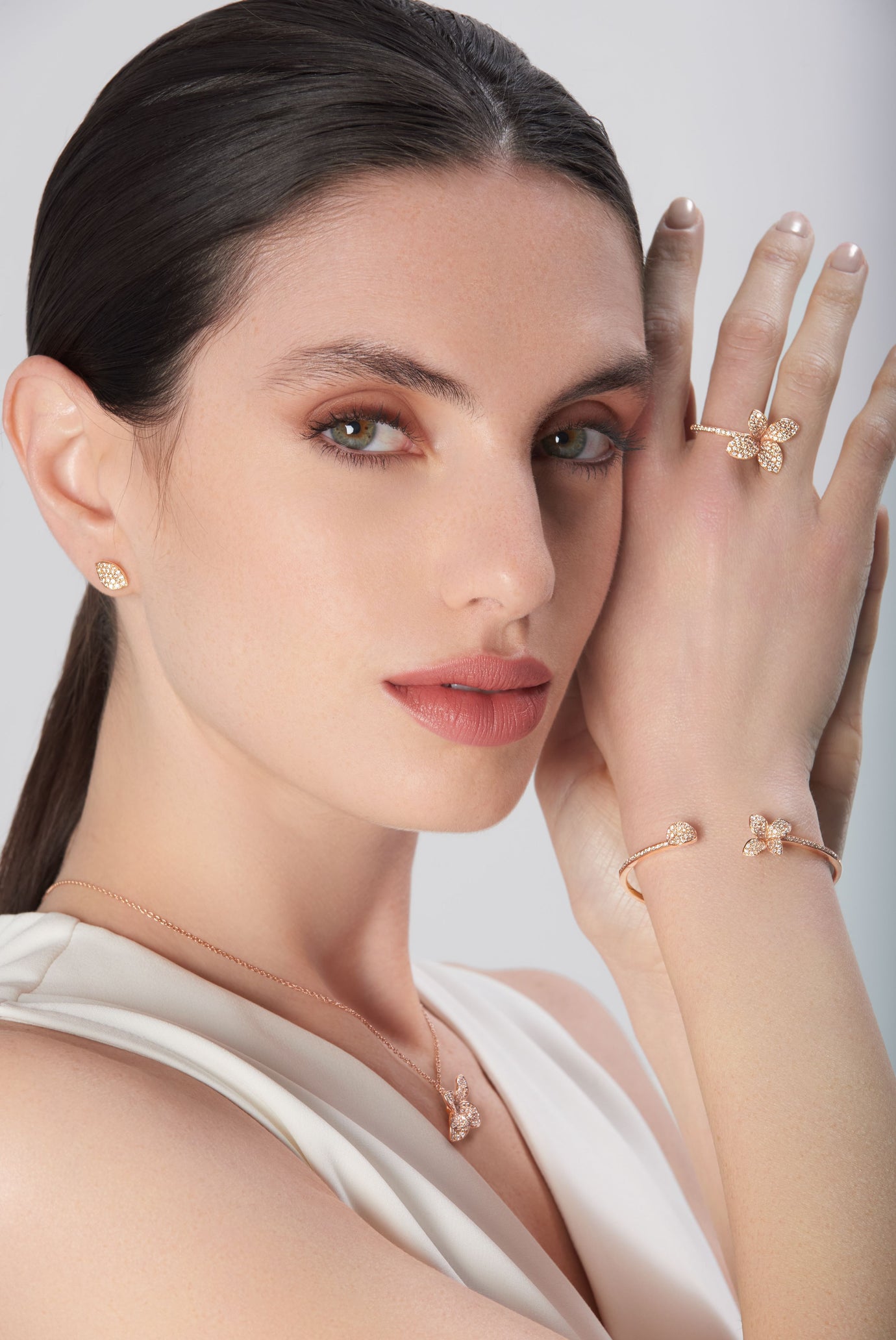 Earrings, necklace, ring, and bracelet in 18k rose gold with diamonds on model in white dress