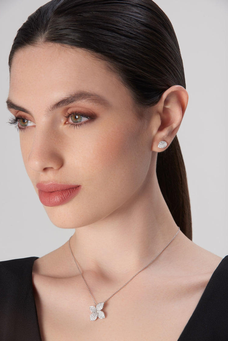 Pendant necklace and stud earrings in 18k white gold with diamonds, worn by model in black dress