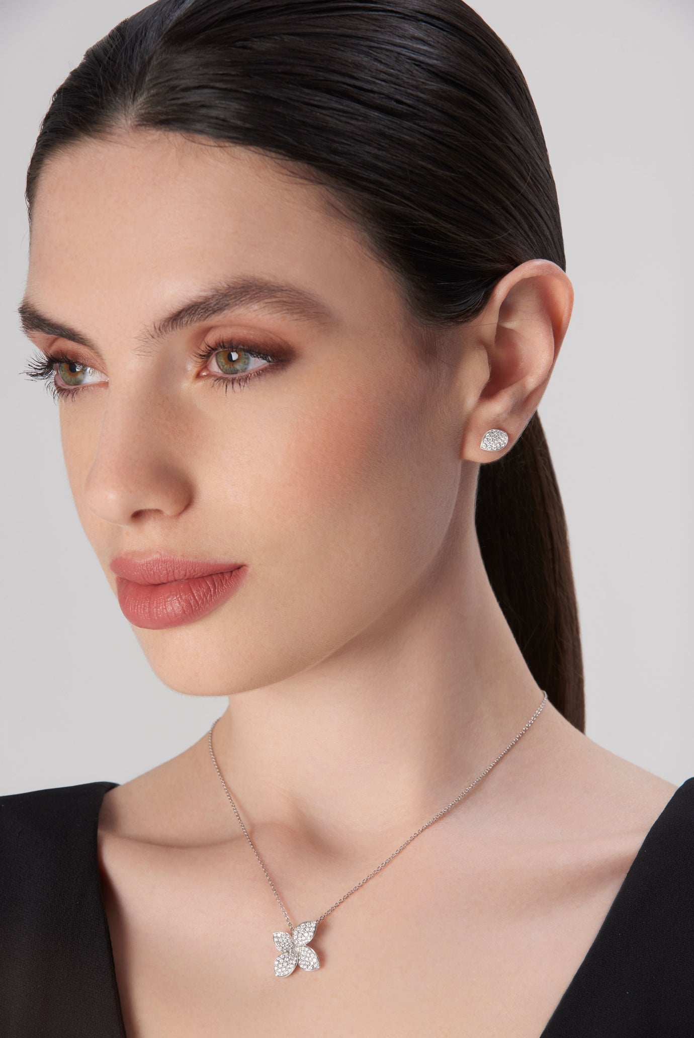 Pendant necklace and stud earrings in 18k white gold with diamonds, worn by model in black dress