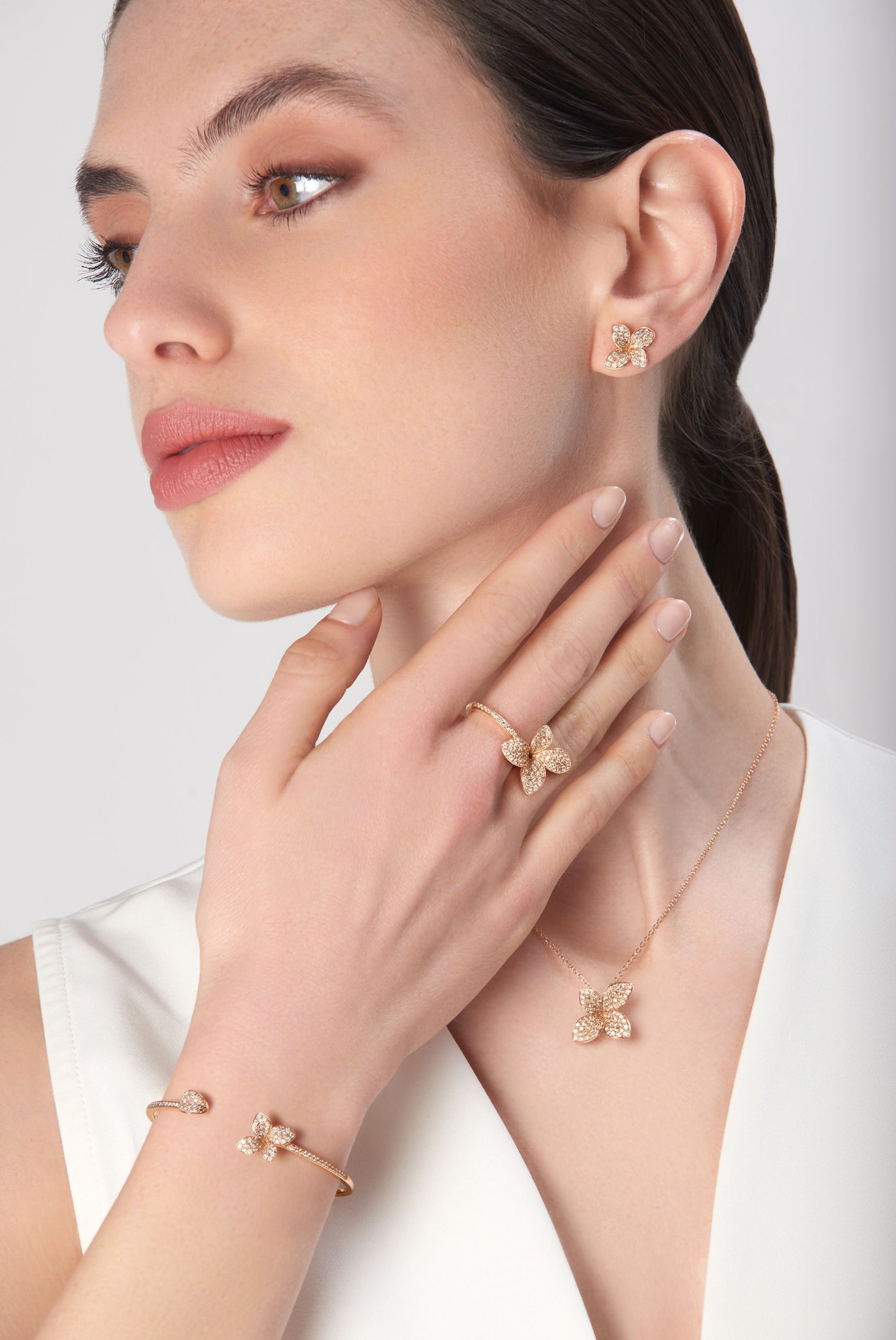 Earrings, bracelet, necklace and ring in 18k rose gold with diamonds on model in white dress