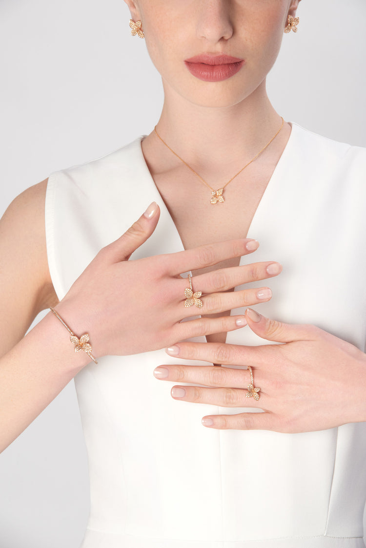 Necklace, earrings, bracelet, and rings in 18k rose gold with diamonds on model wearing white dress