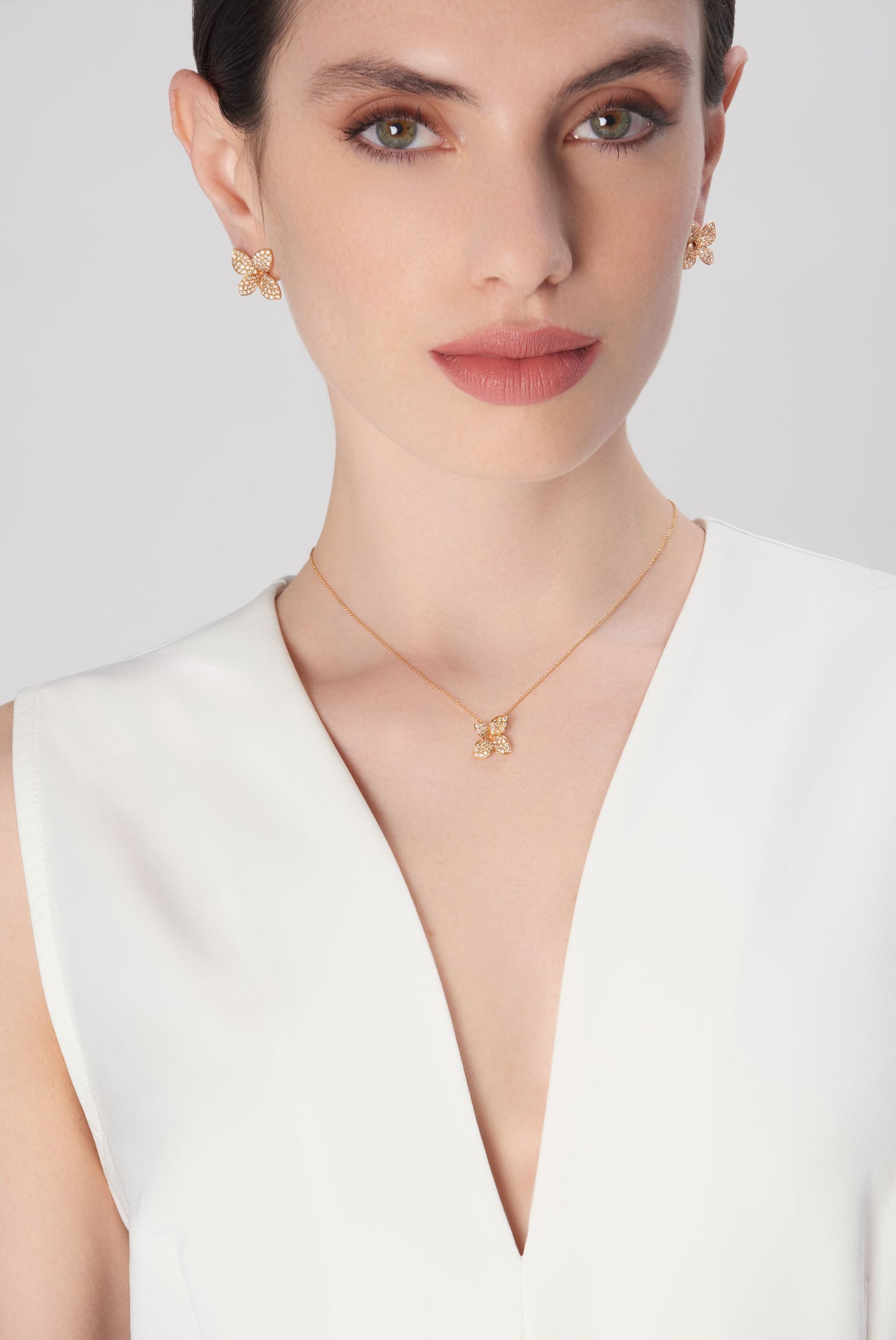 Earrings and necklace in 18k rose gold with diamonds on model in white dress