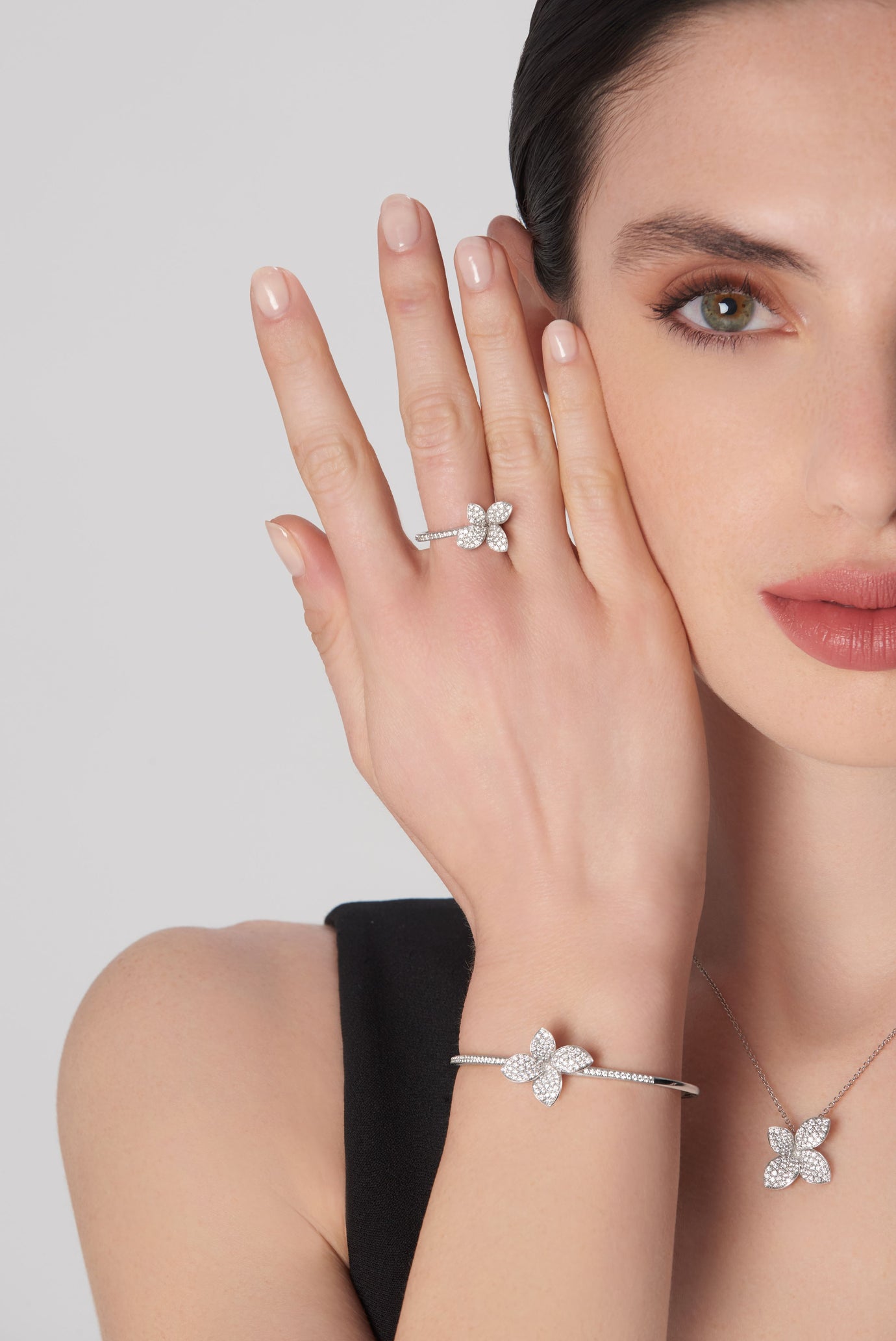 Necklace, ring, and bracelet in 18k white gold with diamonds on model in black dress