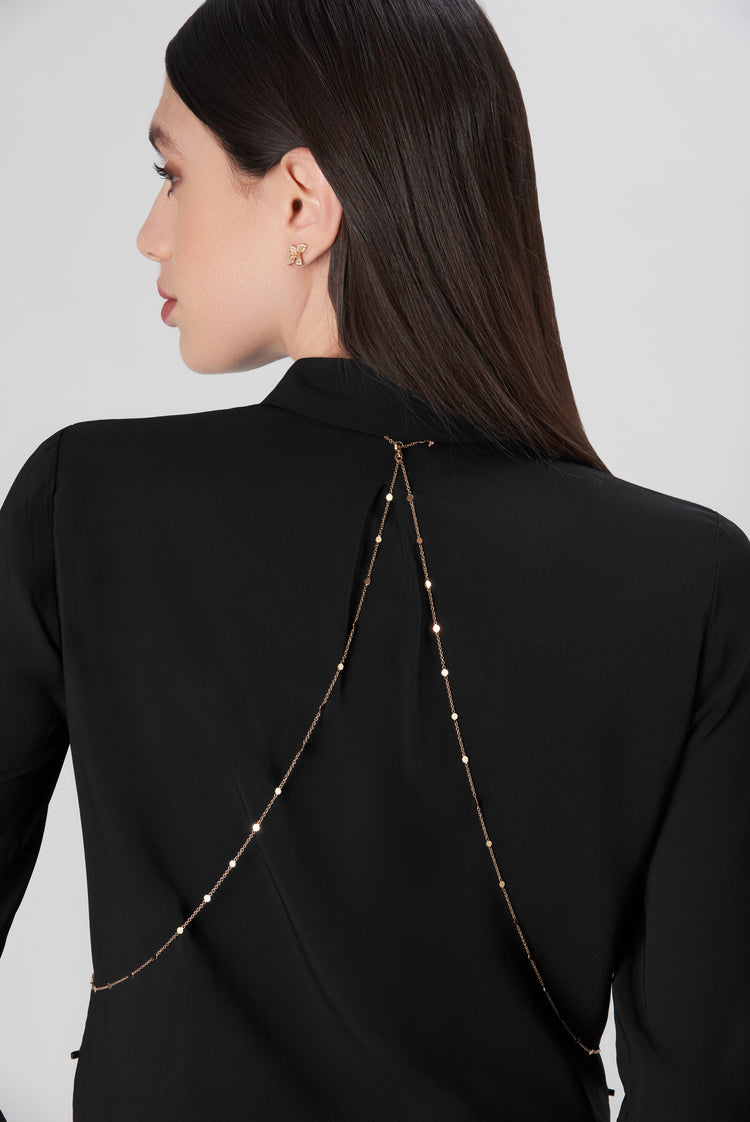 Body chain in 18k rose, white and yellow gold with diamonds worn by a model with a black blouse