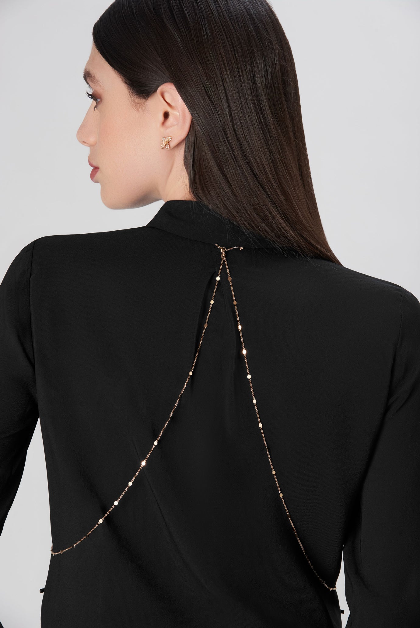 Body chain in 18k rose, white and yellow gold with diamonds worn by a model with a black blouse