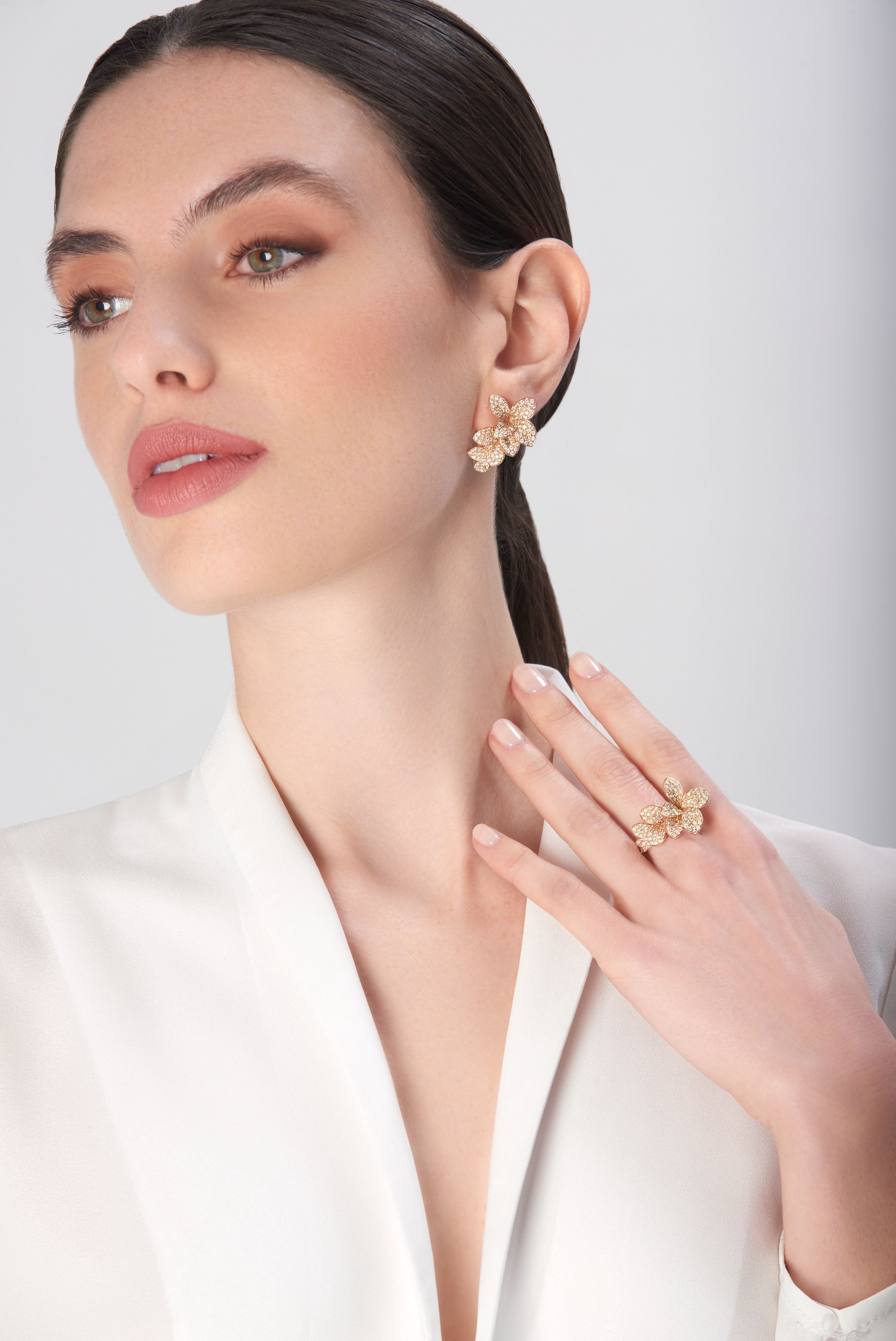 Earrings and ring in 18k rose gold with diamonds worn by model in white blouse