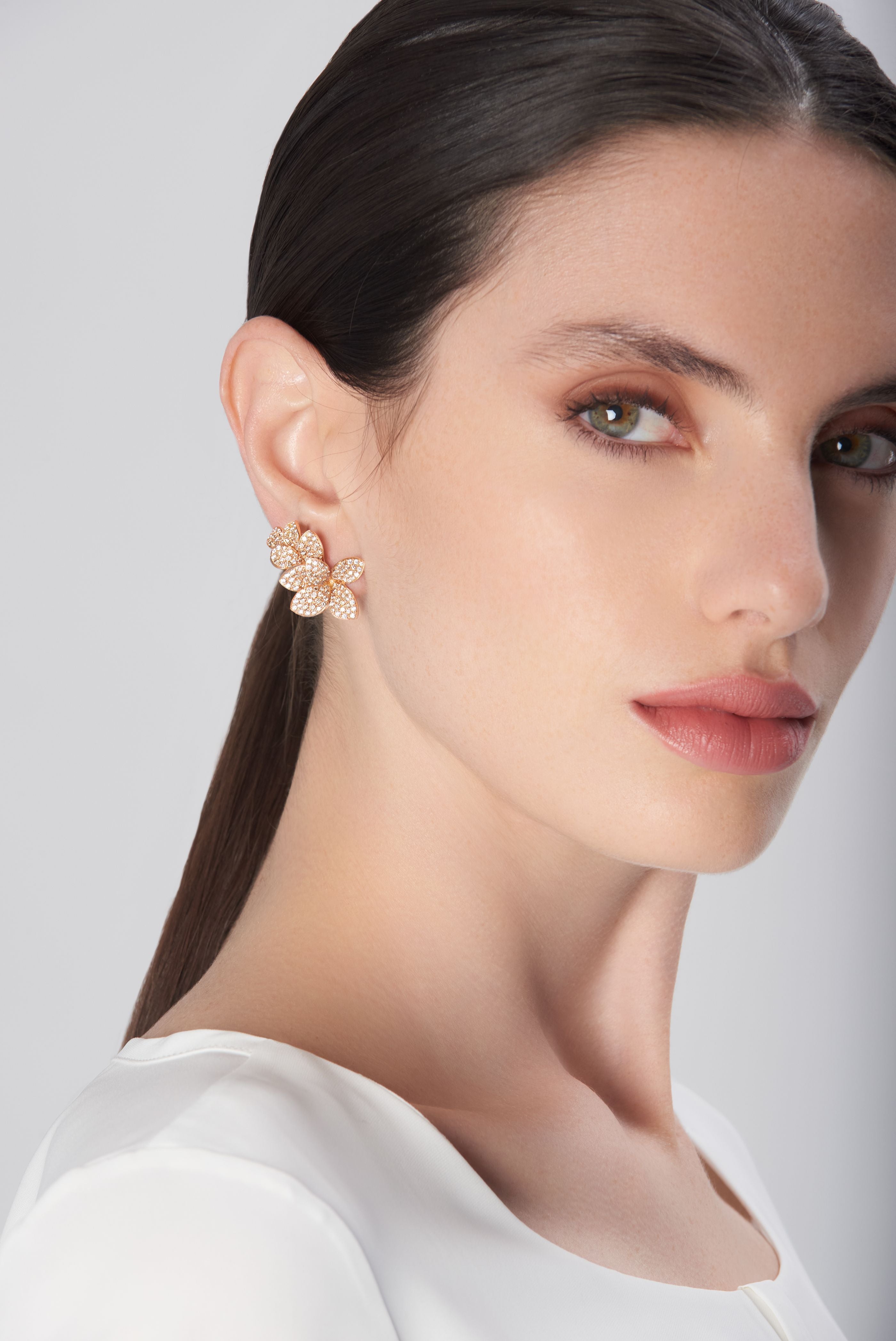 Earrings in 18k rose gold with diamonds on model wearing white silk blouse