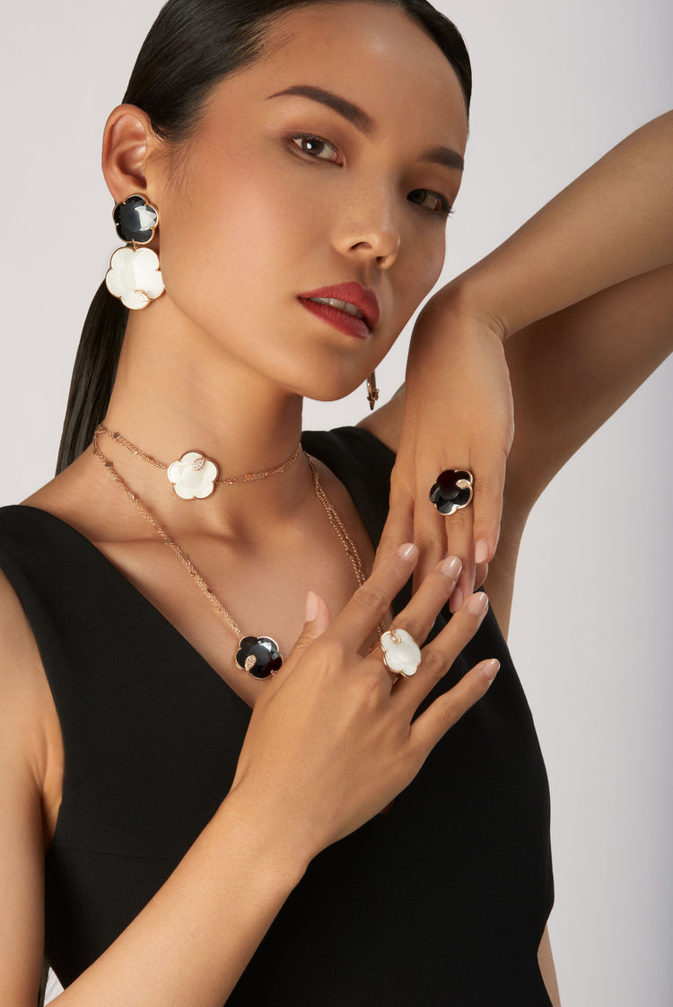 Pendant earrings, long necklace, and rings in 18k rose gold with white and black gemstones with diamond on model in black dress
