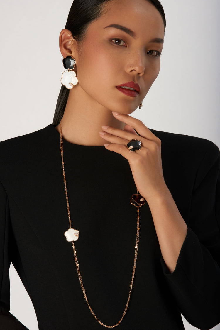 Pendant earrings and long necklace in 18k rose gold with black and white gems and diamonds on model in black dress