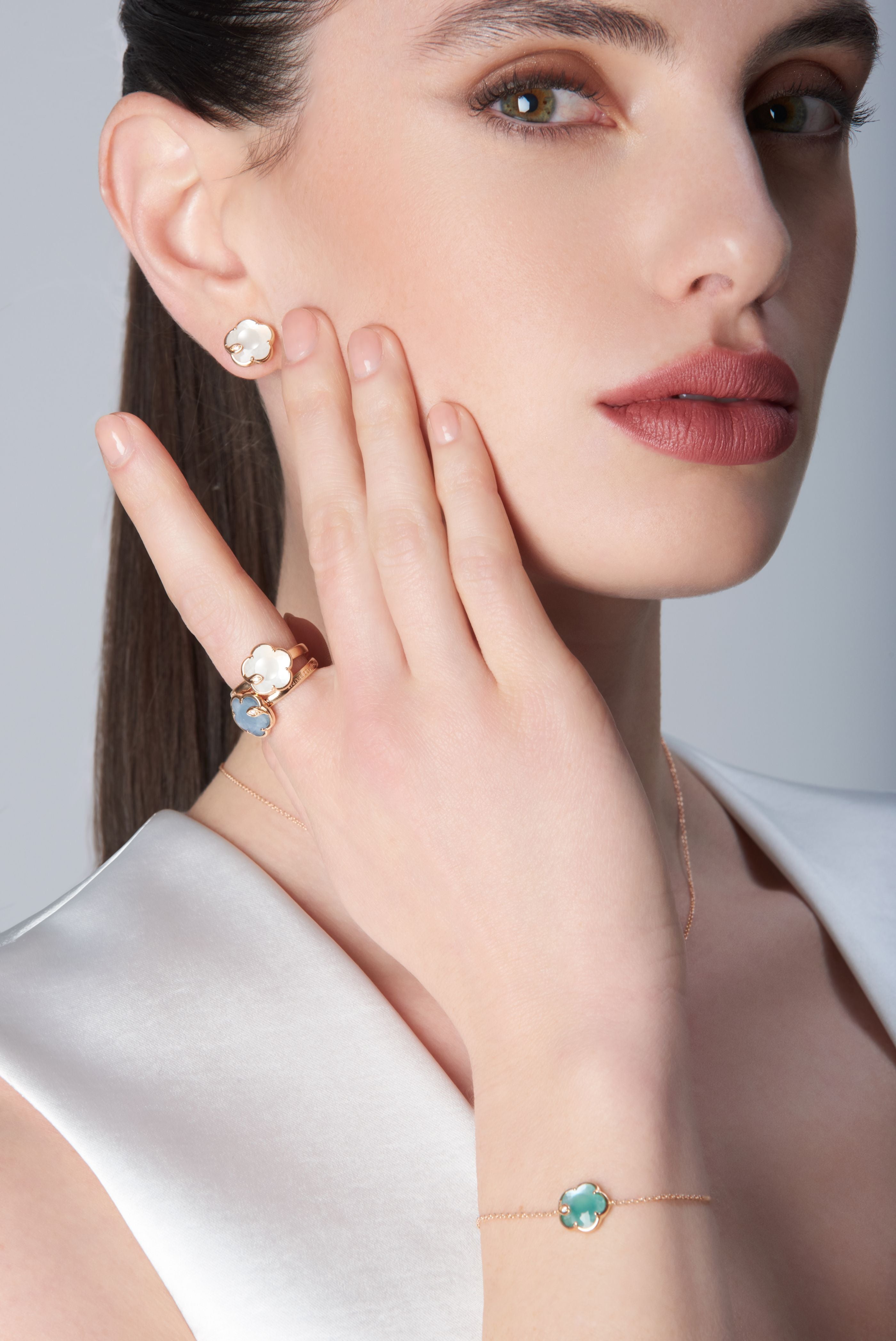 Earrings with pearl gem and diamonds in 18k rose gold and necklace with blue gemstones and diamonds on model in white blouse