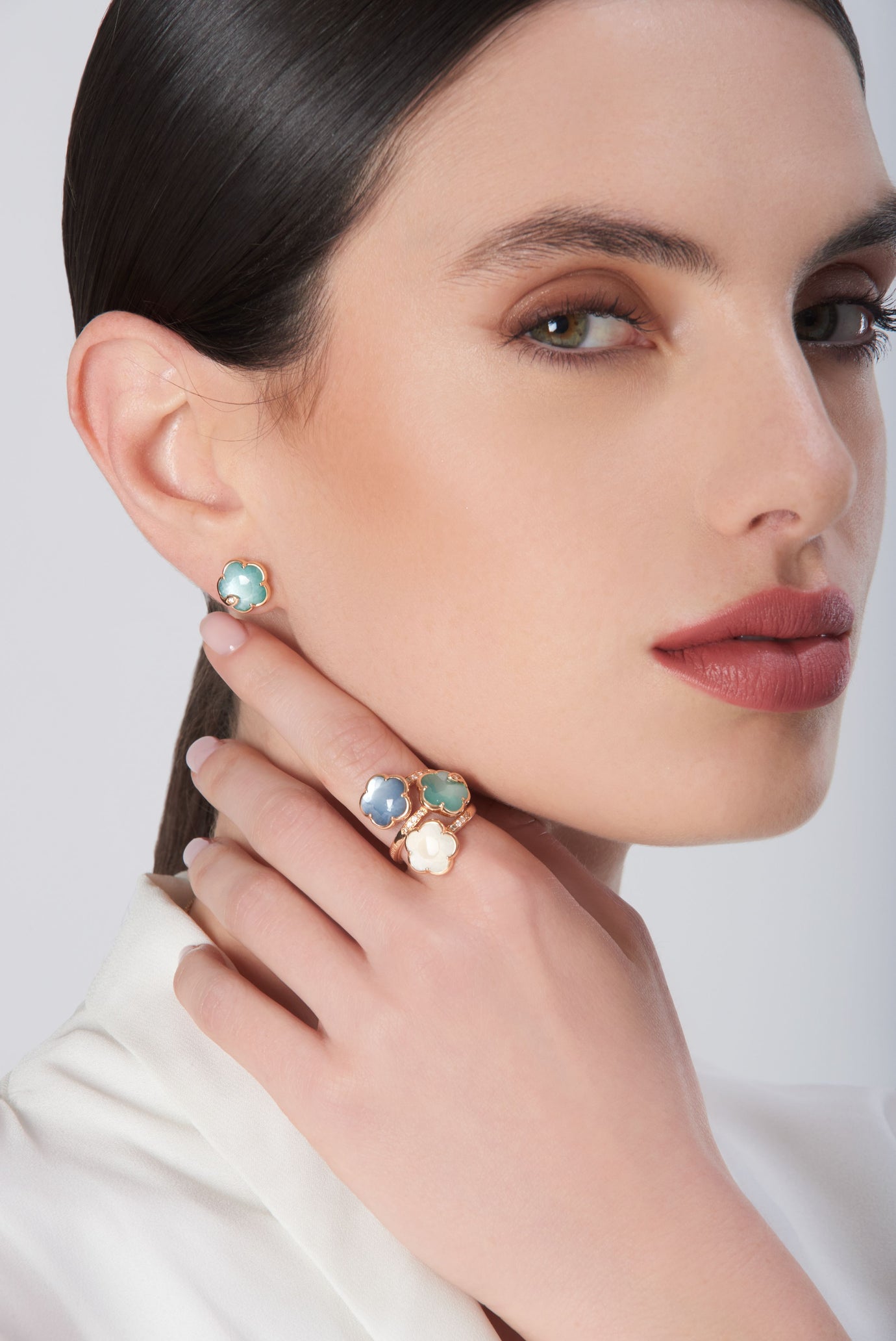 Earrings in 18k rose gold with green gemstone and diamonds and ring in 18k rose gold with colored gemstones and diamonds on model in white blouse