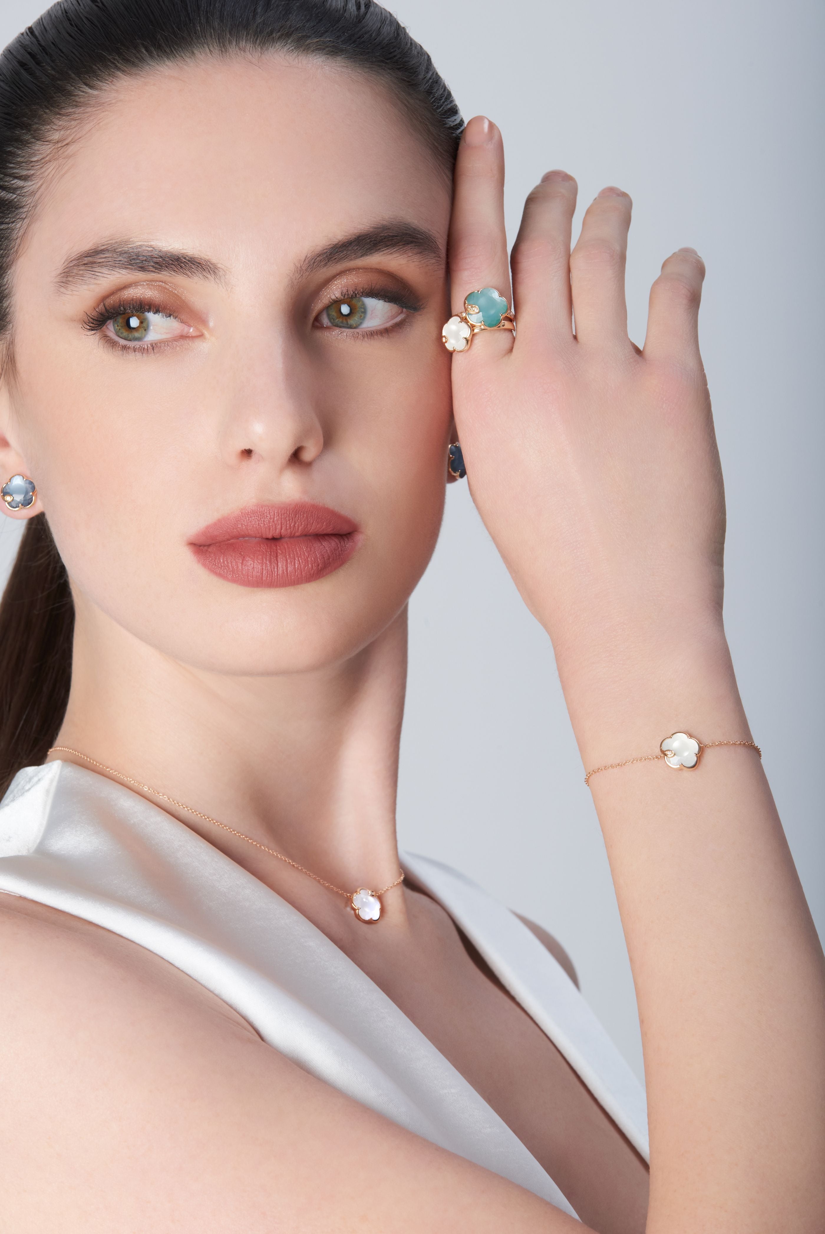 Combination of rings, earrings, necklace and bracelet with coloured gems on model.