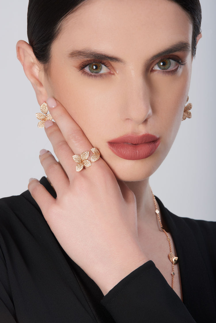 Earrings and ring in 18k rose gold with diamonds worn by a woman in a black dress