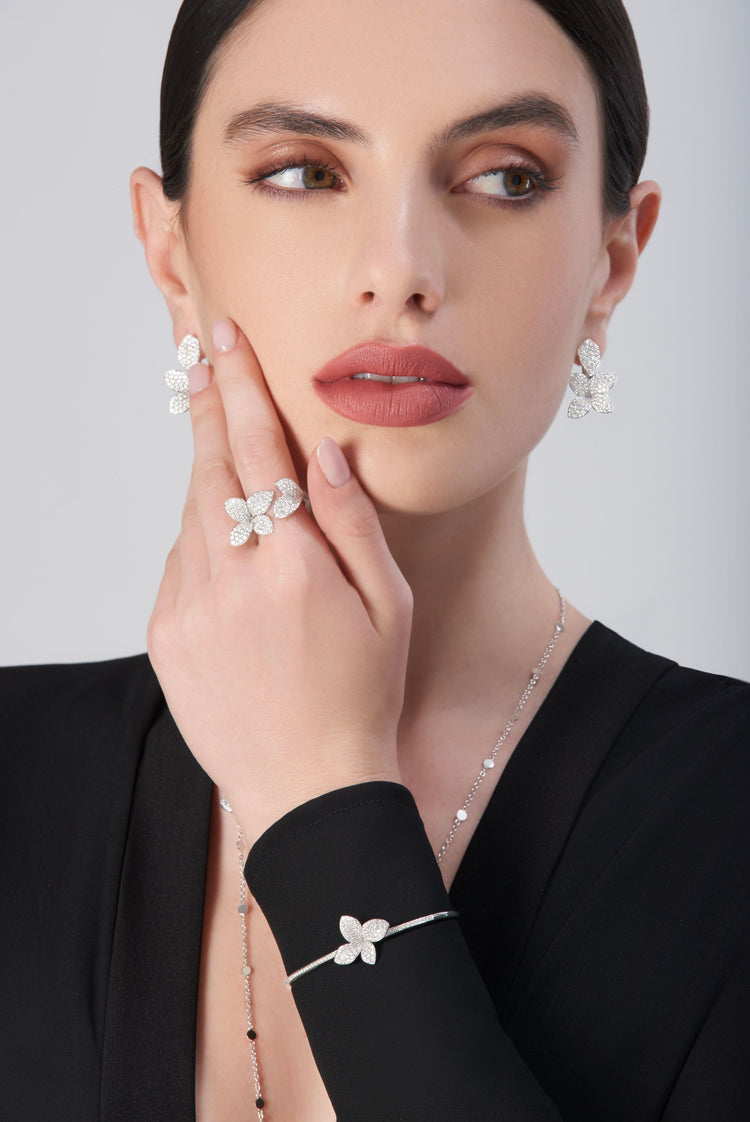 Earrings, ring, and bracelet in 18k white gold with diamonds on model in black dress