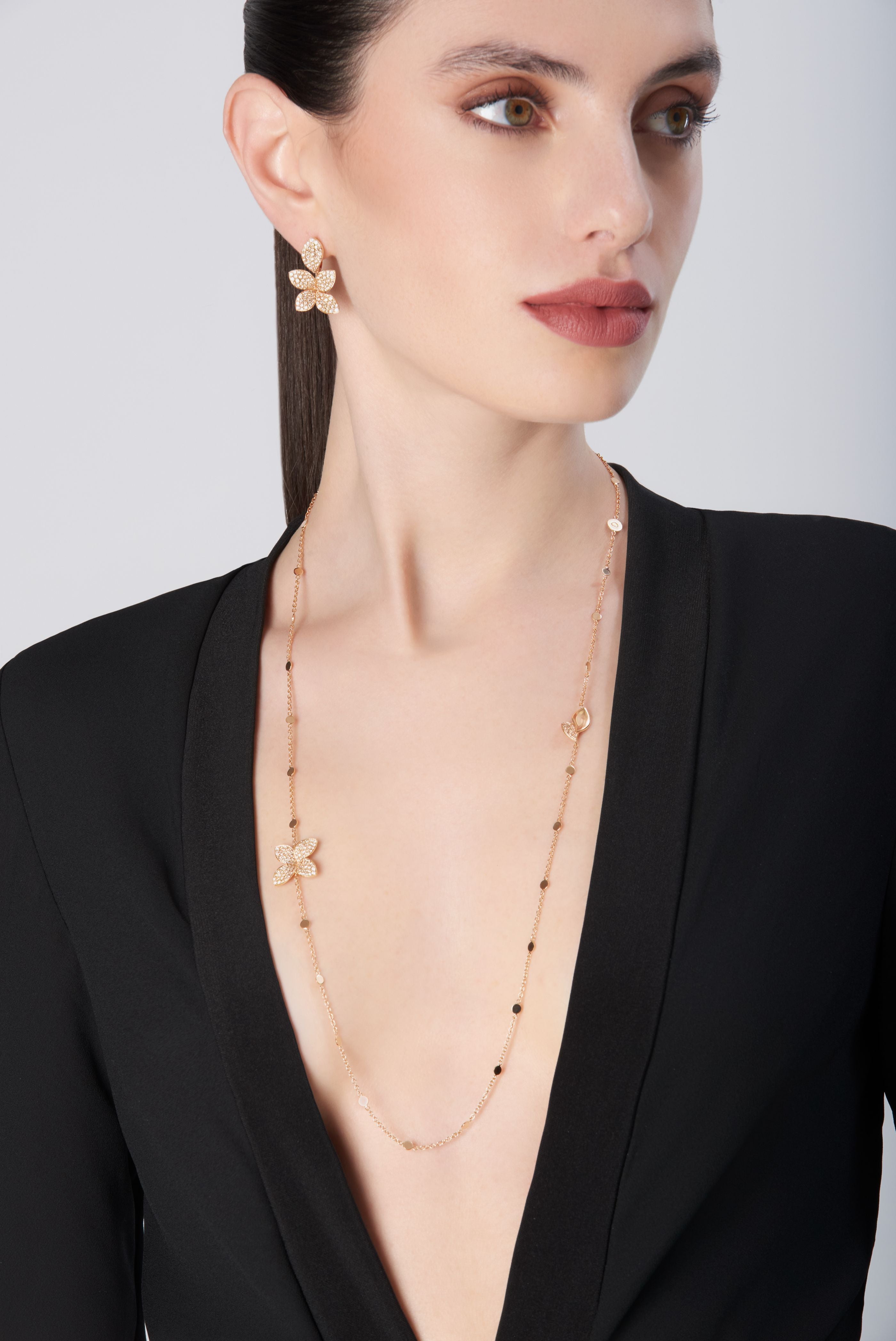 Necklace and earrings in 18k rose gold with diamonds, worn by model in black dress