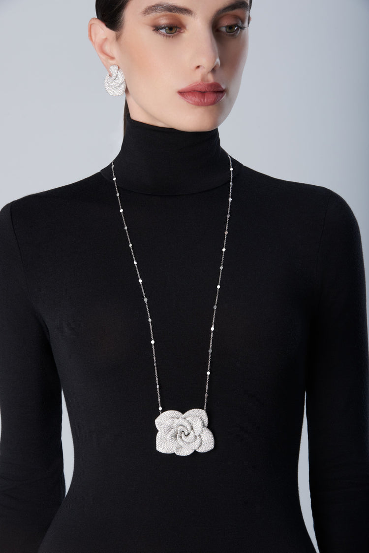 Woman wearing a black turtleneck with a 18k white gold necklace and matching earrings 