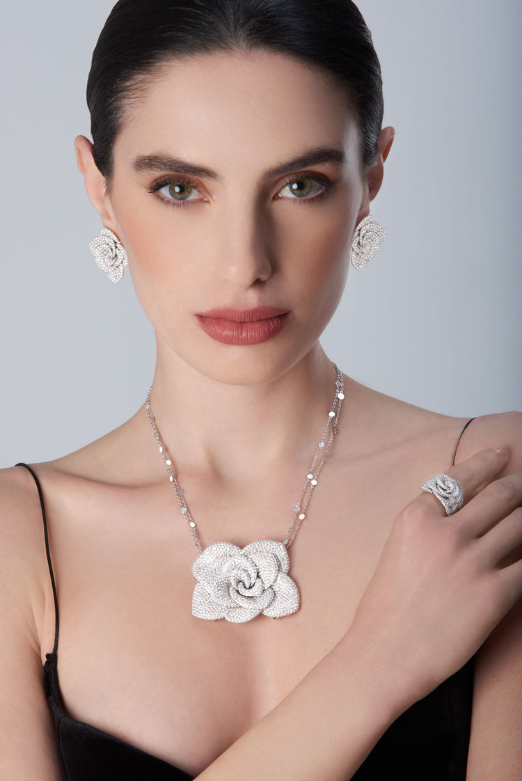 Woman wearing a 18k white gold necklace, ring, and earrings with a black top