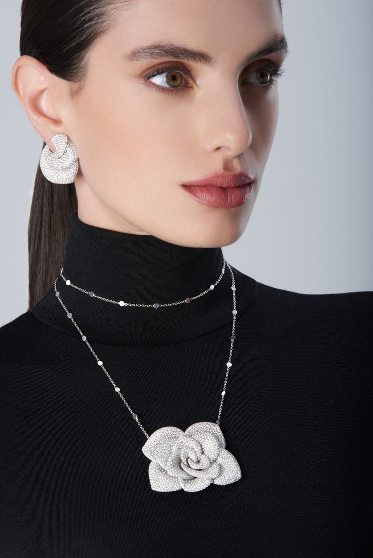 Woman wearing a black turtleneck with a 18k white gold necklace and matching earrings 