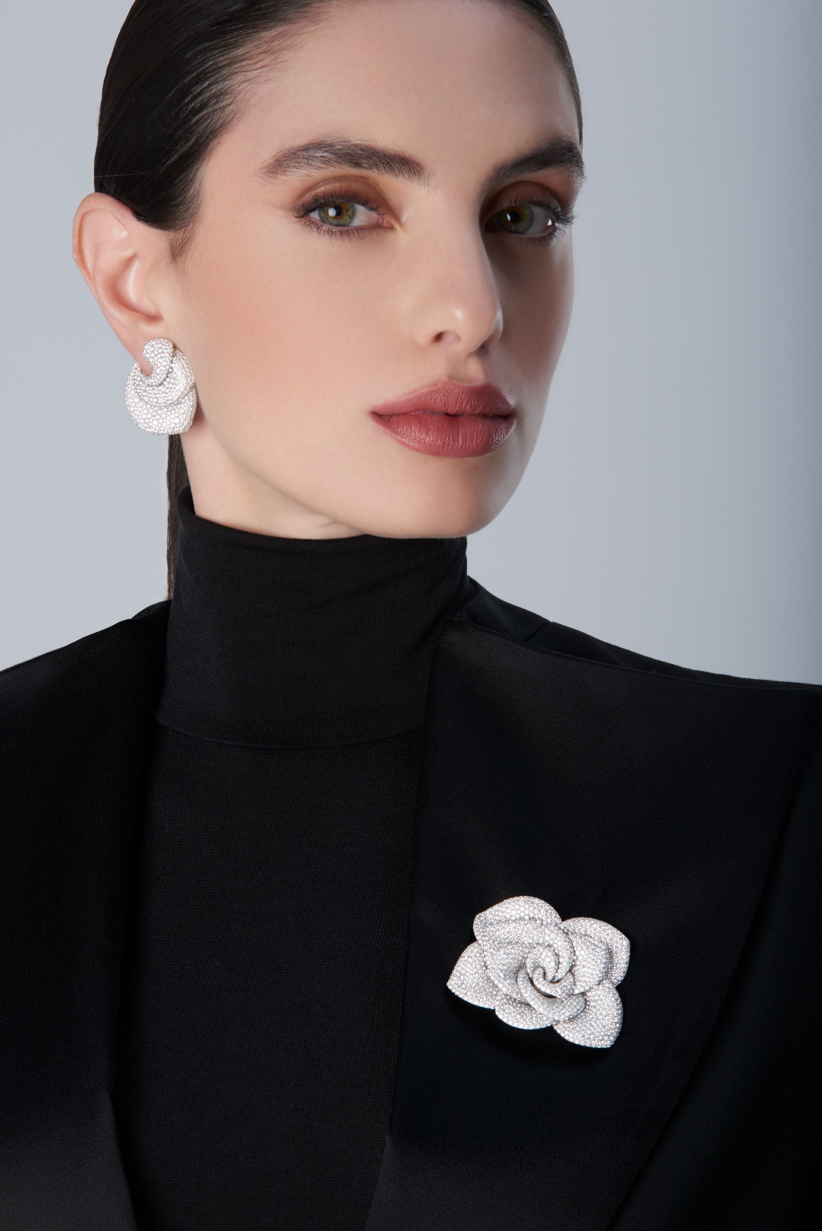 Woman wearing a black turtleneck with a 18k white gold brooch and matching earrings 
