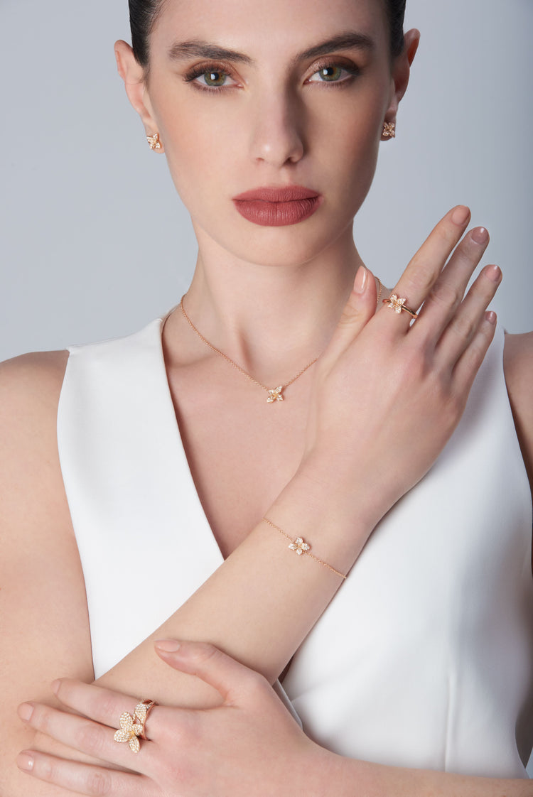 Combination of earrings, necklace, ring and bracelet in 18k Rose Gold with Diamonds on model on model wearing white top