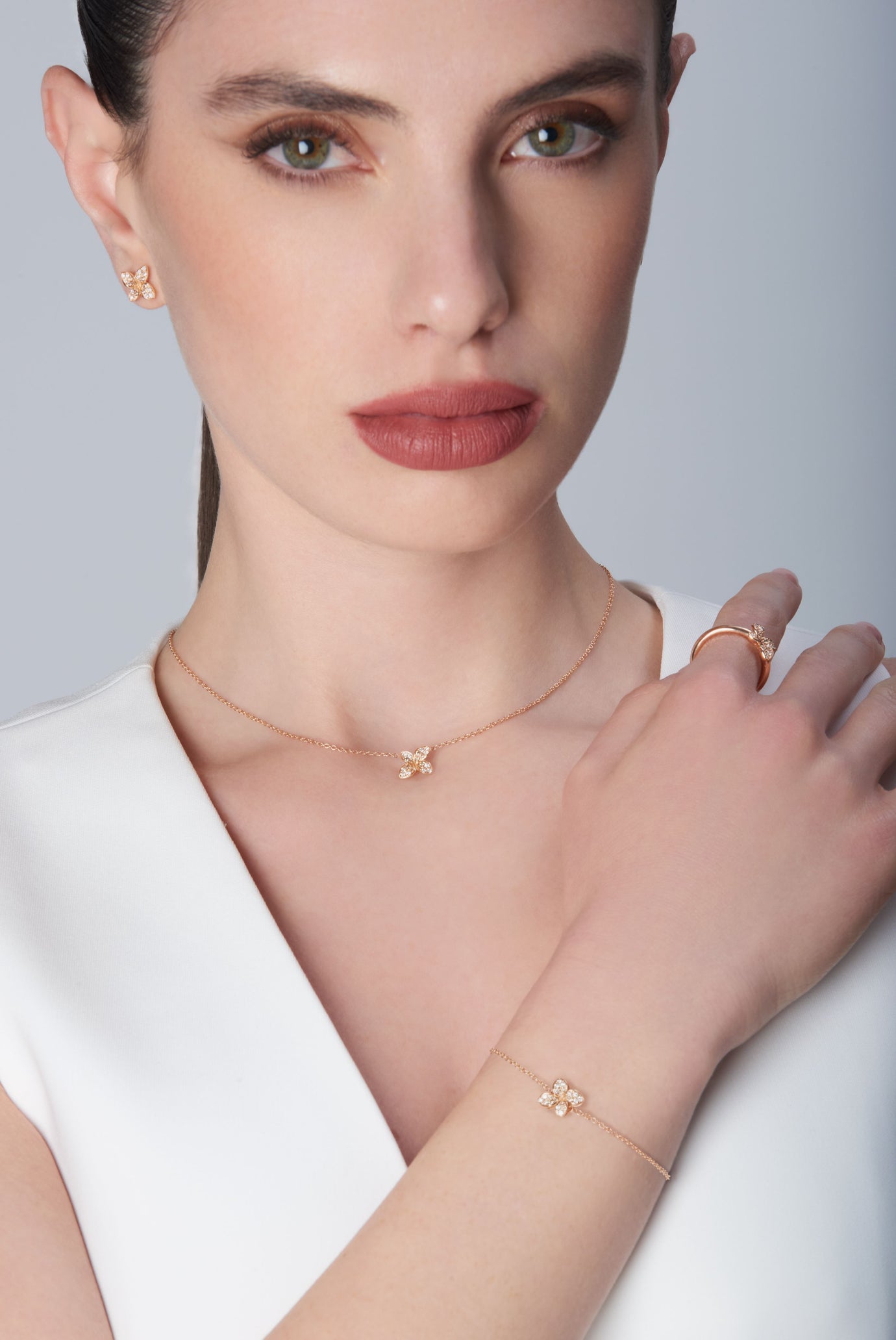 Combination of earrings, necklace and bracelet in 18k Rose Gold with Diamonds on model wearing a white top