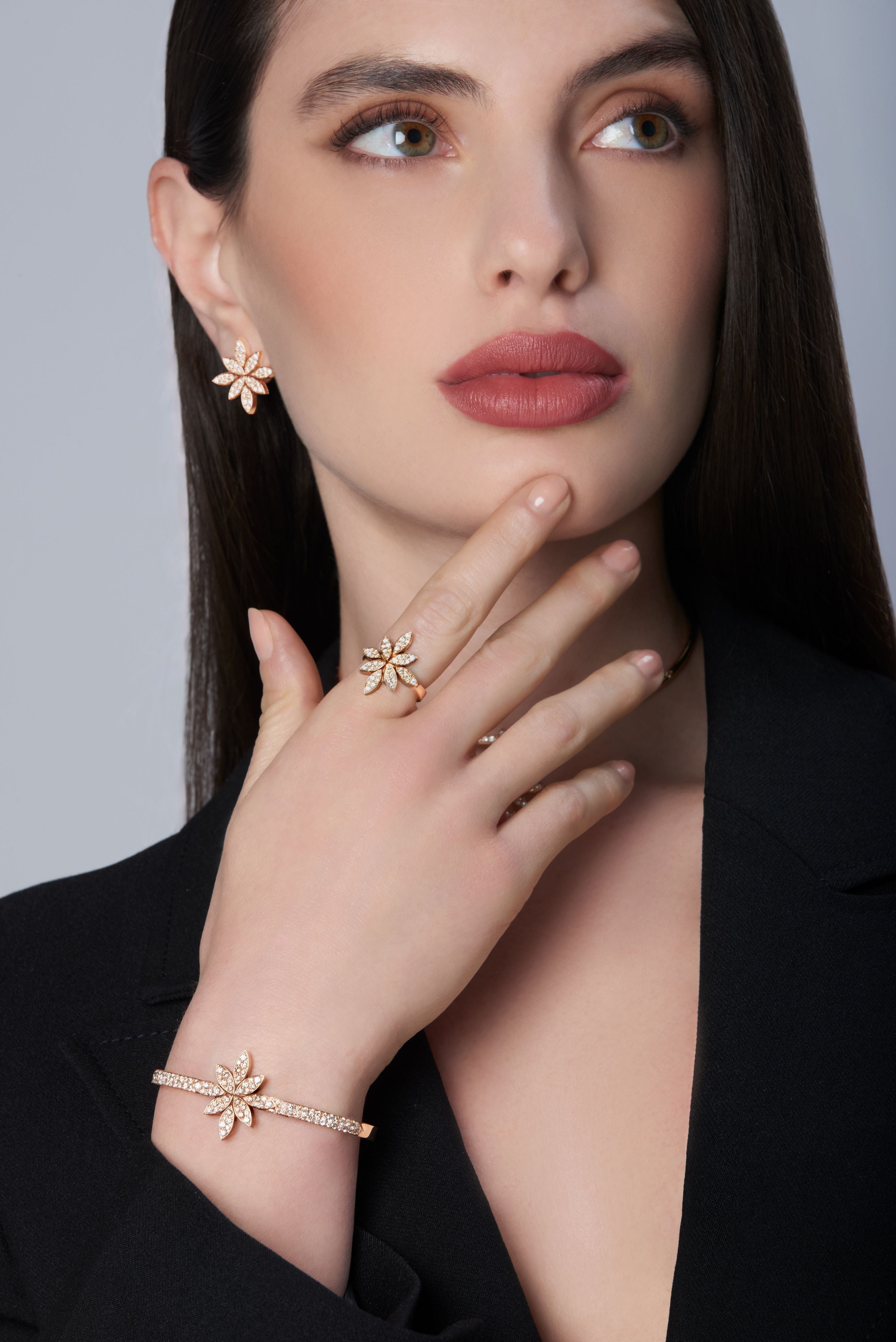 Model wearing a black jacket and earrings, ring and bracelet in 18k Rose Gold with Diamonds
