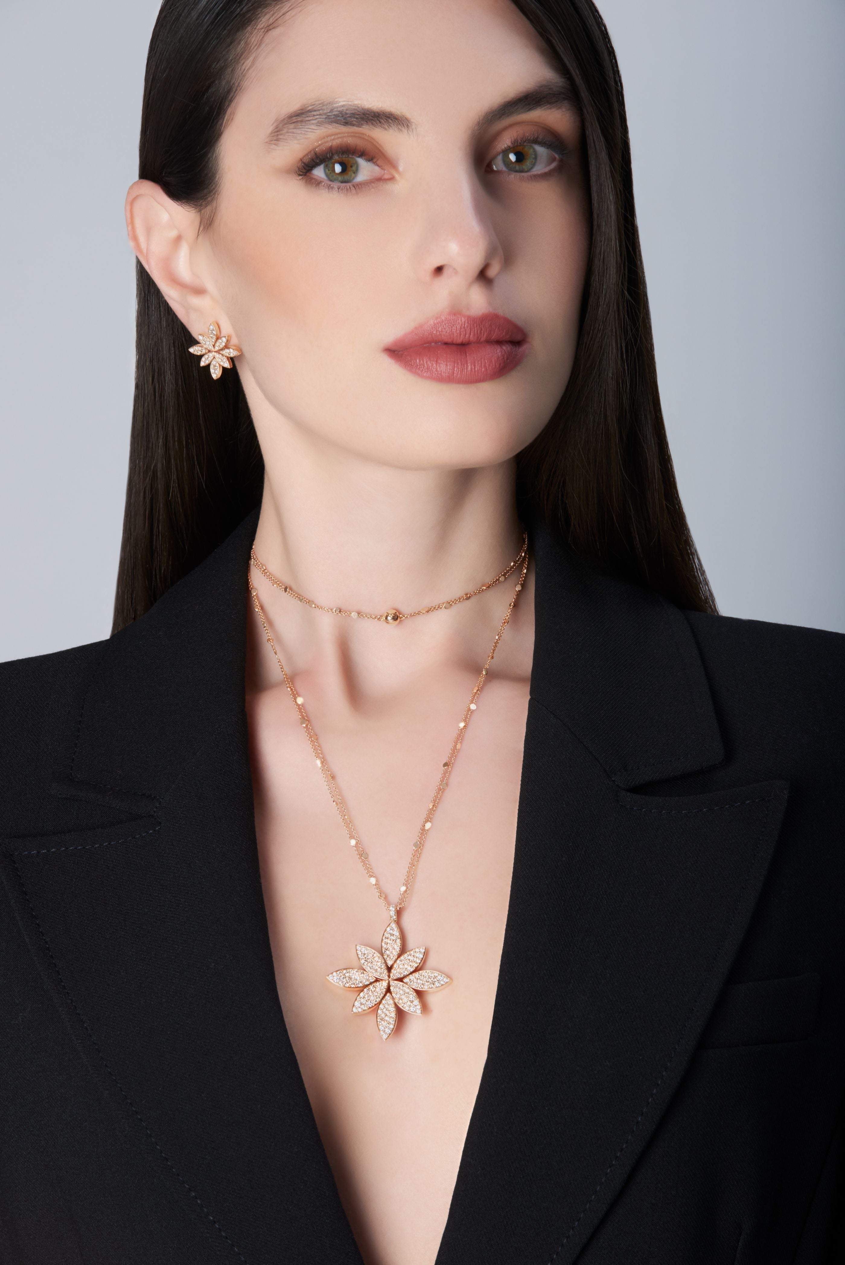 Model wearing a black jacket and earrings and becklace in 18k Rose Gold with Diamonds