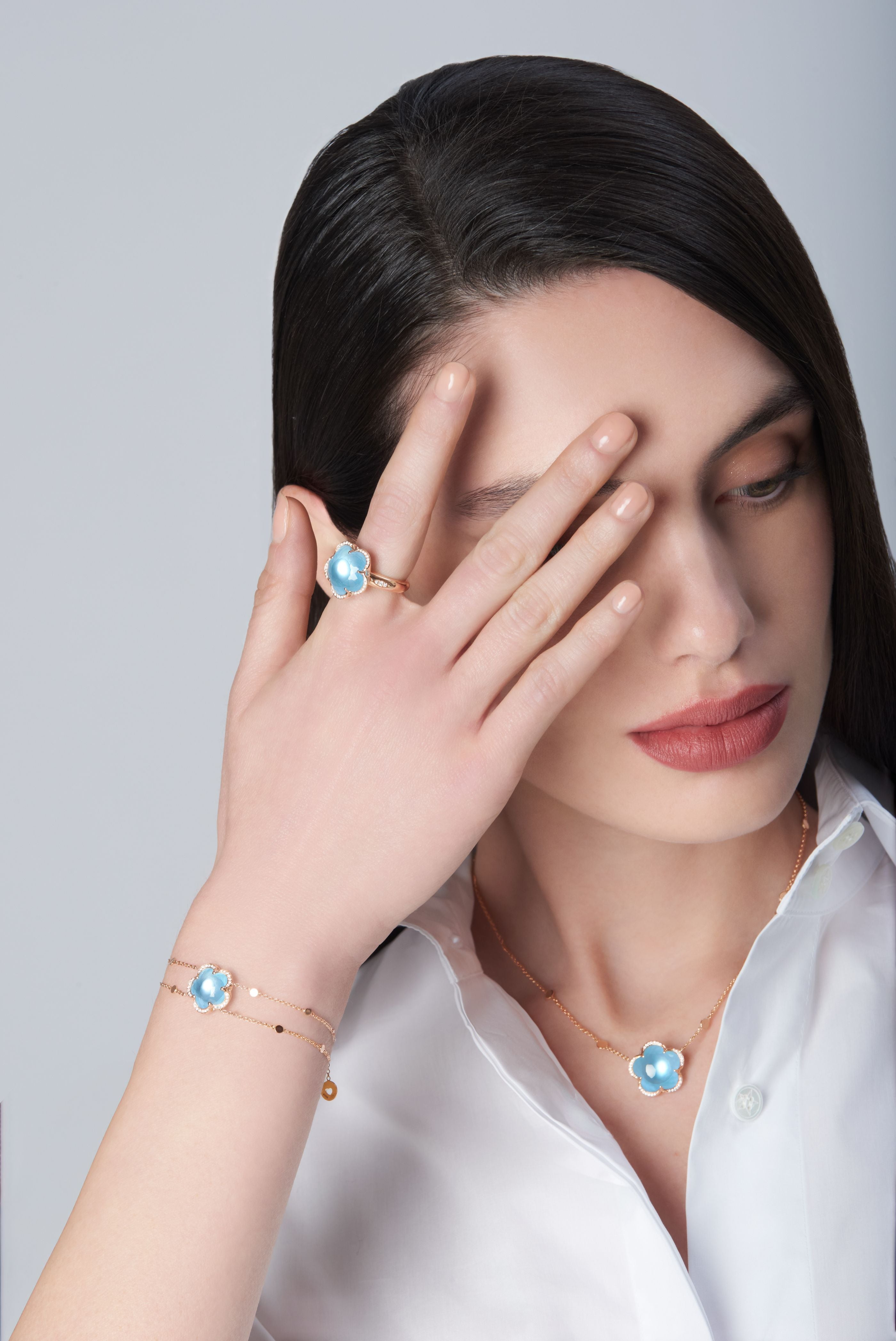 Ring, necklace and bracelet in 18k Rose Gold with Venus Blue Topaz and White Diamonds on model with a white shirt