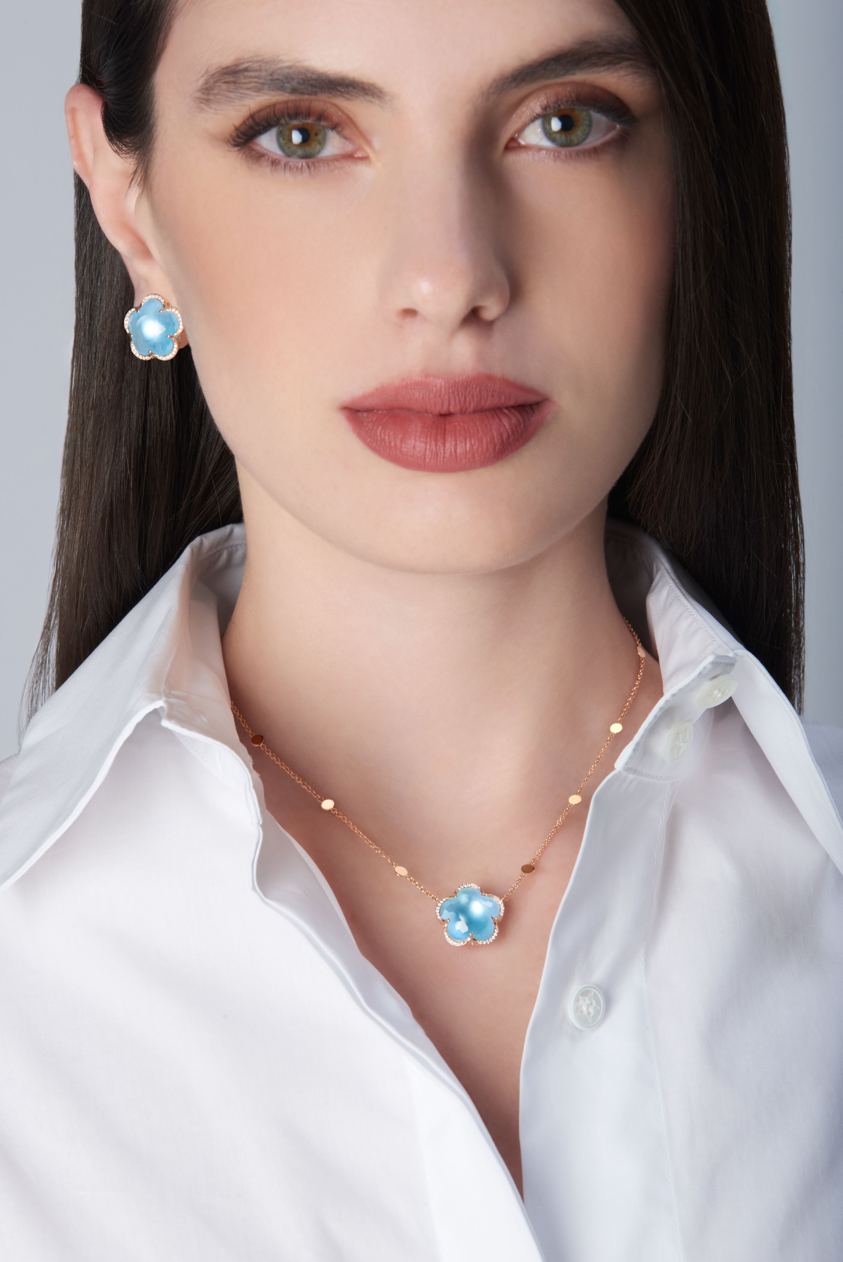Necklace and earrings in 18k Rose Gold with Venus Blue Topaz and White Diamonds on model with white shirt