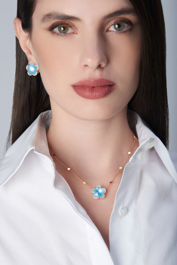 Necklace and earrings in 18k Rose Gold with Venus Blue Topaz and White Diamonds on model with white shirt