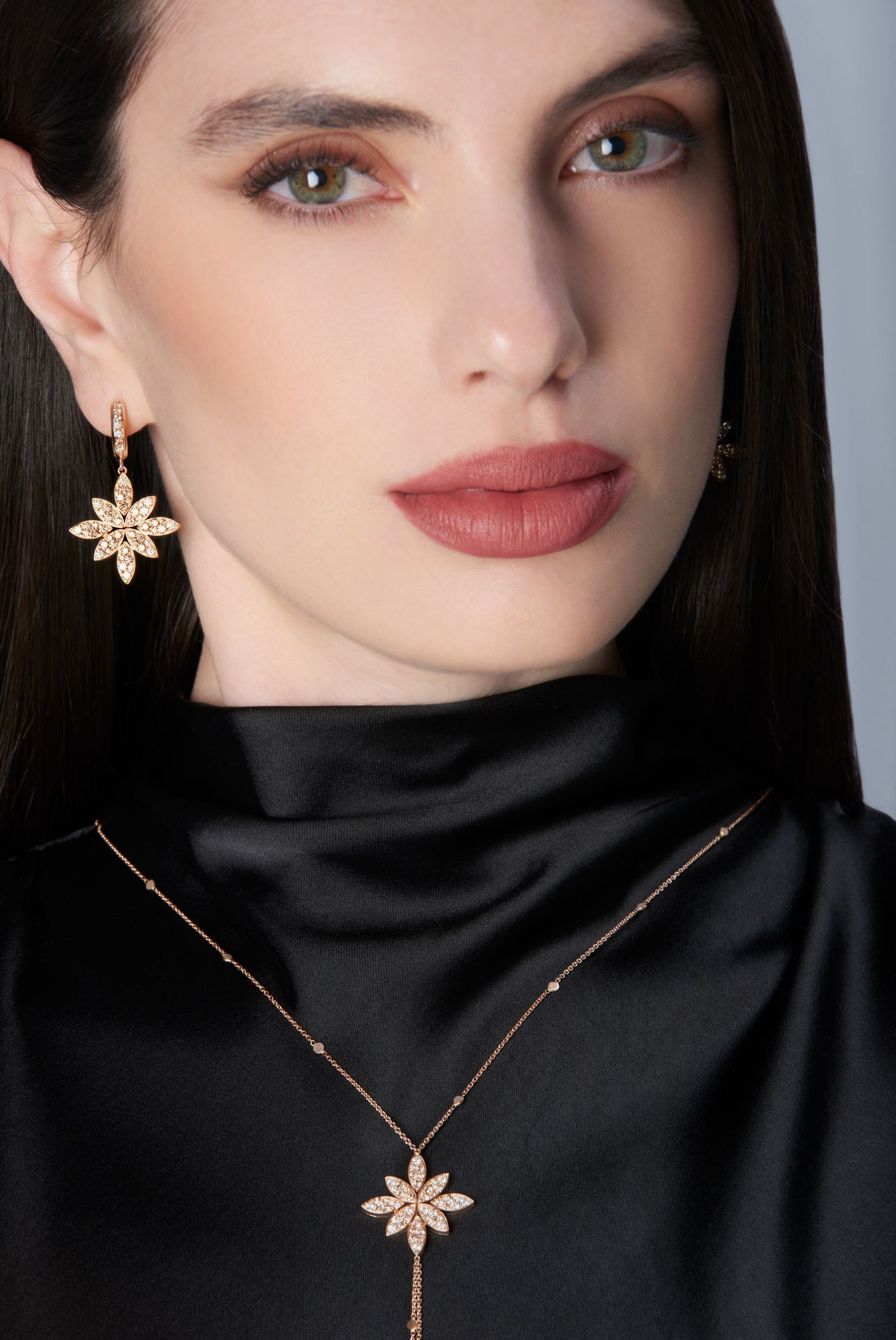 Close-up of a woman wearing a black top and gold earrings with diamonds.