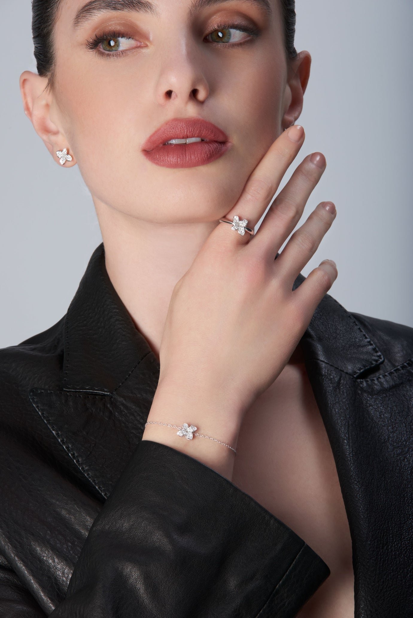Combination of earrings, ring and bracelet in 18k White Gold with White Diamonds on model wearing black leather jacket