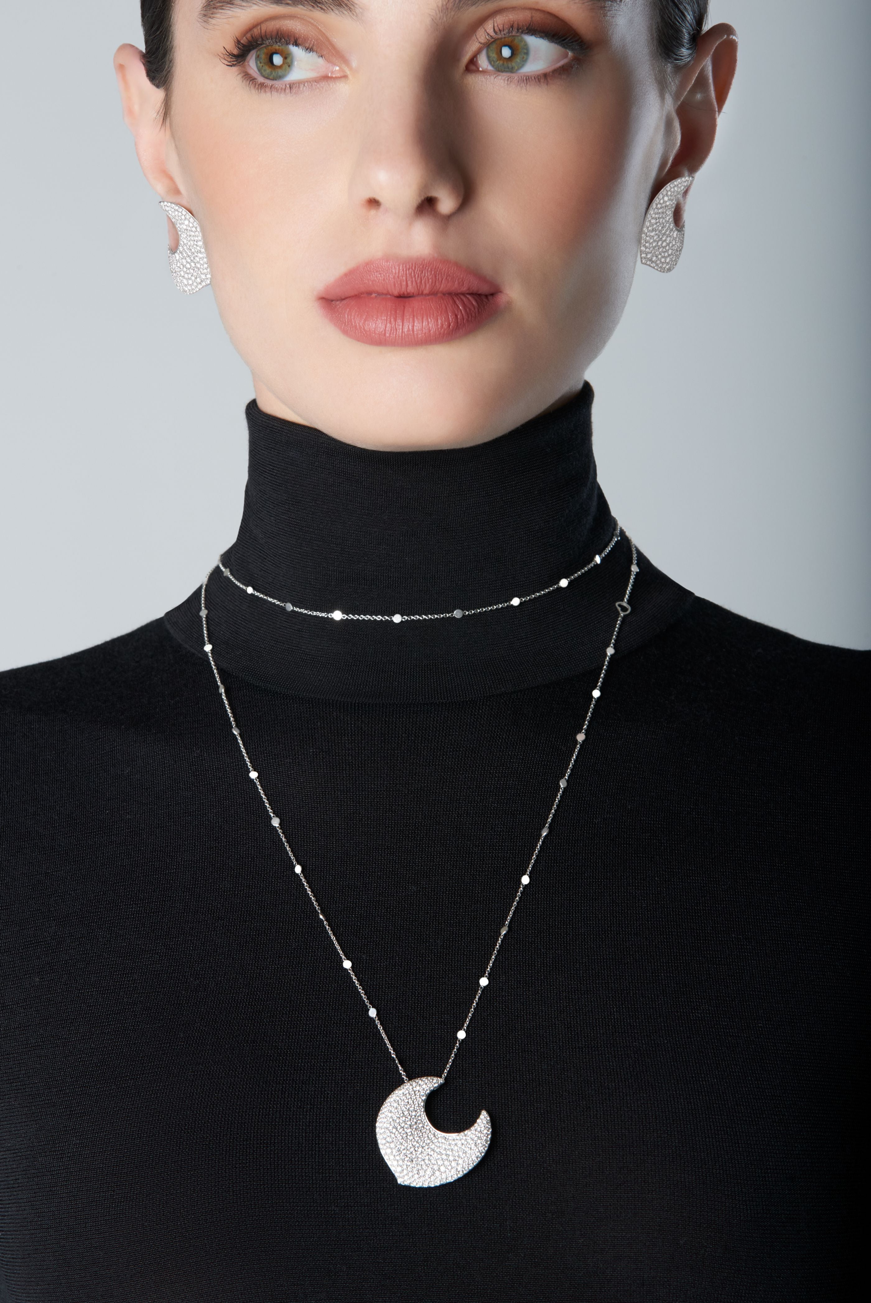 Woman wearing diamond earrings and necklace in 18k White Gold with white diamonds